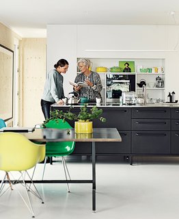 The couple have crafted their own kitchens in the past. For their floating home, however, they selected the black Vipp kitchen, where Juul chats with her daughter, Karla. 