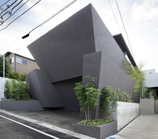 Concrete planters frame the facade—a union of monolithic slabs that offers privacy and compositional integrity to the building. The exterior is a plaster finish over insulation and concrete.