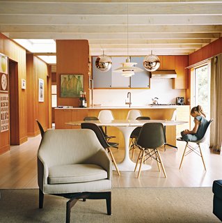 The open-plan living-kitchen-dining area is a repository of design icons, both classic and contemporary. There’s a Louis Poulsen pendant lamp over the Eero Saarinen dining table; Mirror Ball pendants by Tom Dixon over the kitchen counter; and Tab F1 floor lamps from Flos behind the Edward Wormley–designed Dunbar sofa. In the living room, chairs modeled on Jens Risom’s swivel design enable people to face either the sofa or to spin 180 degrees toward the kitchen.