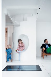 Resident Peter Østergaard (with Maja, 6, and Carl, 20 months) and architect and photographer Jonas Bjerre-Poulsen have been best friends since they were 13, which makes for easy collaboration. Says Bjerre-Poulsen: "There are always a lot of challenges in a renovation, but Peter and Åsa trusted my judgment and gave me a completely free hand. Usually it’s hard to push people into unconventional solutions, but Peter has all these wild and crazy ideas." One such idea was to embed a transparent glass-and-iron door in the floor, operated by a hydraulic pump, which allows access to the subterranean wine cellar. At night, the lit-up cellar glows, lending the compact living room an increased sense of verticality.