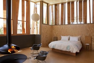 In the master bedroom the Fireplace is by Fireorb, the rocking chairs are by Ray and Charles Eames for Herman Miller, and the bed and bedside table are custom designs by the owners.
