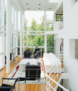 The current homeowners, Michael McCarthy and Marcia Myers, pictured at home in the Douglas Residence, spent years rehabilitating the structure. The double-height living room features a custom sofa and low table of Meier’s design, and an Edward Fields rug based on a sketch Le Corbusier created in 1956 for a Tokyo theater.