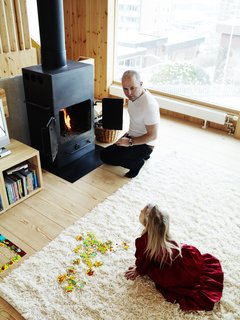 Knotty by Nature - Photo 3 of 25 - Architect Per Bornstein and his daughter Velma relax in the living room. The woodburning stove was a second-hand store find.