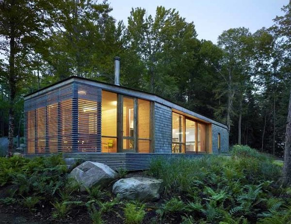 Sited on a lake near Bracebridge, Ontario, this small-footprint family cottage was designed by Toronto firm superkül to integrate with its natural surroundings and minimize its environmental impact. The clients, a married couple, had mixed feelings about going completely modern with their cabin's aesthetic, so the architects created a sculptural wood form to bridge the gap between traditional and contemporary. Photo by Shai Gil. Photo of Stealth Cabin modern home
