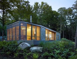Sited on a lake near Bracebridge, Ontario, this small-footprint family cottage was designed by Toronto firm superkül to integrate with its natural surroundings and minimize its environmental impact. The clients, a married couple, had mixed feelings about going completely modern with their cabin's aesthetic, so the architects created a sculptural wood form to bridge the gap between traditional and contemporary. Photo by Shai Gil.