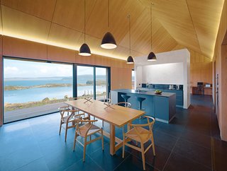 A Pitched-Roof Dwelling on Scotland's Isle of Skye - Photo 1 of 2 - Hans Wegner Wishbone chairs surround a custom table by Mary Arnold-Forster. The pendant lamps are by Bestlite.