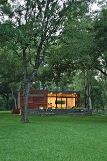 In a family’s pint-size lake retreat in Austin, Texas, ipe siding and decking meet concrete floors and steeland-glass windows. Stained cyprus was used for the ceiling and soffit. The custom barn-style sliding door conceals the family’s collection of giant inner tubes and other boating equipment. Photo by: Kimberly Davis
