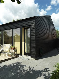 30 All-Black Exterior Modern Homes - Photo 3 of 30 - Since Copenhagen is generally cold, the house was painted black to trap warmth. The result was that in its first year, it consumed so little energy that the client received a generous refund from the heating company. "Many wooden houses in Scandinavia use this trick," Larsen says. "On sunny days it even radiates warmth, so that in spring and autumn you can sit outside by the wall and in this way extend the outdoor season by a few weeks every year. These weeks are valuable in places with little light."