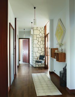 Modern Home Furnished With Flea Market Finds - Photo 13 of 17 - Shelves from Danish company We Do Wood, pendants by Uno & Osten Kristensson, a rug by Pappelina, and a vintage chair adorn the entry hallway. The wood doors and frames are original.