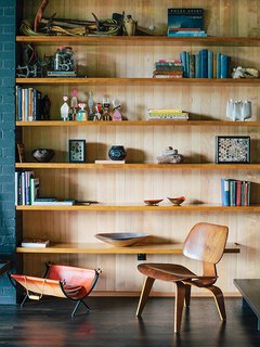 A vintage Molded Plywood Lounge Chair (LCW) by Charles and Ray Eames for Herman Miller sits in front of built-in shelving in untreated hemlock.