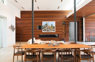 Ipe paneling and concrete floors continue into this living area, where a photograph by Scott McFarland hangs above the fireplace. Surrounding the dining table, by Riva 1920, are walnut chairs.