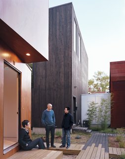 Four Houses and a Future - Photo 8 of 11 - Schenk, Kim, and Kaewlai chat outside of X-Small, standing on the reclaimed wood used to build the boardwalks that connect all four properties. The translucent corridor connecting Small and Medium illuminates the common space throughout the evening.