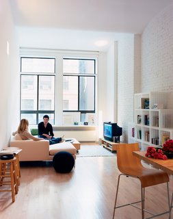 A reflective light shelf sits atop the lower window units. "When light hits the shelf, it reflects back on the ceiling," Woo explains. "This is a very deep space, so we tried to bring the light as far back as possible." The Neo sectional chaise by Niels Bendsten provides comfortable seating for Wonbo and his friend Alyssa Litoff. The Cubits shelves are by Doron Lachish.