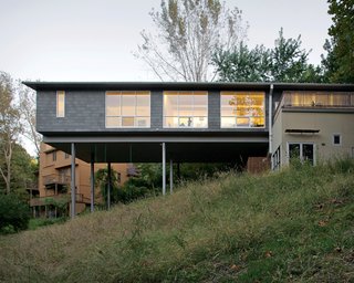 The Arnolds’ bedroom and living area float over the hillside, the large windows allowing light to flood in from both sides. A bamboo-enclosed deck sits atop the house’s foundation.