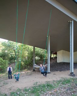 Julie, James, and Christian enjoy an unexpected bonus of living in a house on stilts—–a pair of swings suspended from the base of the structure. The family often goes for walks on the property, looking for wildlife and playing in the tepee they built in a secluded space in the woods.