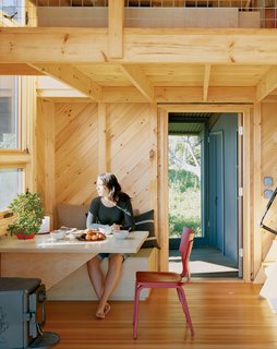 Alex enjoys a sun-filled breakfast at the built-in dining table and bench, one of many space-saving designs.