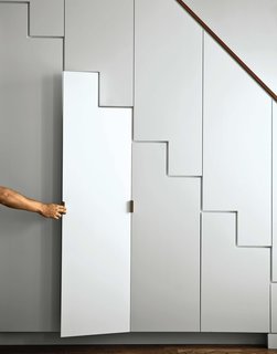 The apartment’s main stairwell, disguised as a Shaker cabinet–meets–Japanese tansu stair, houses storage for kitchen ephemera. The finish is hand-painted and accessorized with raw brass hardware.