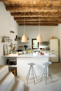 25 Homes With Exposed Beams: Rustic to Modern - Photo 4 of 25 - In Nani Marquina's serene home in Ibiza, Jamaica barstools by Pepe Cortès for Knoll and two Ikea pendants pair nicely with the plaster walls, restored wooden beam ceilings, and polished cement floors in the kitchen.