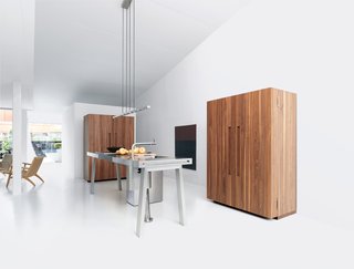 Bulthaup's b2 system comes equipped with everything a kitchen needs—the workbench contains a sink, trash receptacles, and cooktops, while the two wooden cabinets house the appliances and the kitchenware.