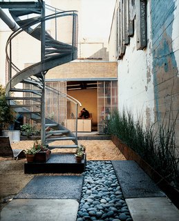 A spiral staircase descends from the glass deck to the rain garden, which replaced a concrete pad.
