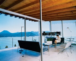 Loredana Dall’ Amico reads in the living room, where all the seating was designed by her husband. The floating stainless steel unit behind her is also his design and contains a state-of-the-art stereo system.