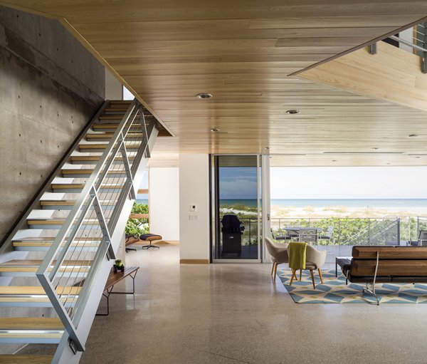 10 Enclosed Porches That Are Put to Good Use - Photo 8 of 10 - A 24-foot sliding glass door system leads out onto the balcony from the great room. Cypress wraps the ceiling and floor above. Beck says, "In designing this project, we strove for simplicity. Cost efficiencies were obtained by exposing the structure where possible, taking advantage of locally sourced products, and choosing relatively simple finishes." For the floor, a local concrete company ground and polished the elevated slabs to create the finished floors and exterior staircases.