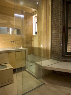 Chan outfitted the bathroom in marine fir plywood from Rosenzweig Lumber for its resistance to high-moisture environments. The fixtures are from Vola; the bathtub, countertop and sinks are of magnesite. The full-height glass is stationary except for a sliding door at left, and a curtain can be rolled down for privacy.