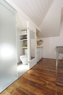 Tips for Tiny Bathrooms - Photo 11 of 12 - Azevedo shoehorned a small bathroom next to the kitchen, under the dormer. The etched translucent glass lets light into the main living area and serves as one side of the shower. Photo by Susanne Friedrich.