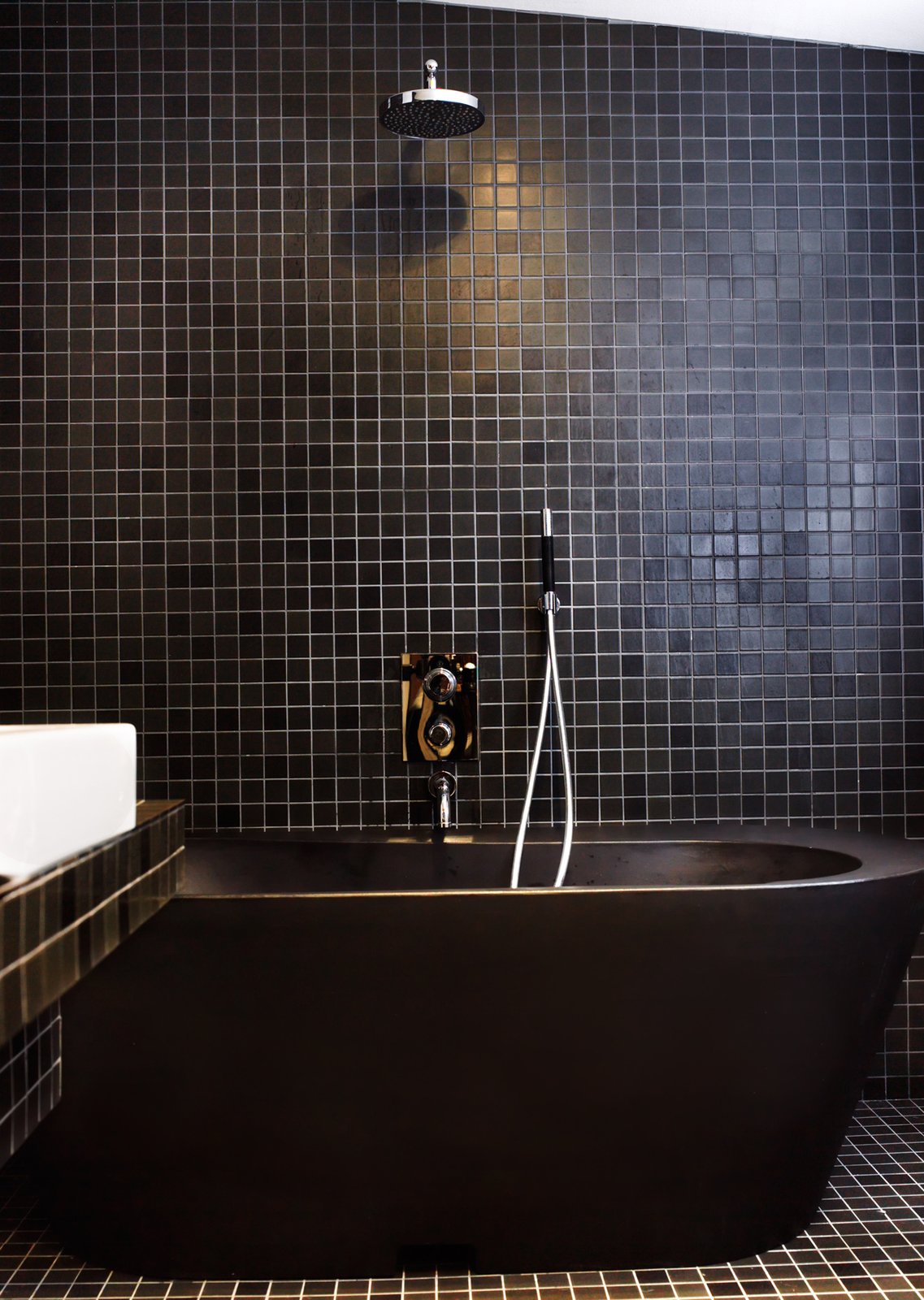 Black tiles and fittings lend the bathroom a dramatic look. The black bathtub is made of recycled plastic.