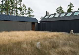 Linden specified a black stain from Cabot for the house’s exterior. The shade draws on Scandinavian and Japanese building traditions and helps the structure blend into the landscape. Native grasses populate the courtyard.