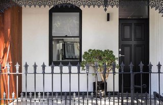 Renovated 19th-Century Terrace House Merges with the Outdoors - Photo 1 of 7 - The home’s white stucco walls and chestnut-hued timber offer a modern contrast to its filigree railing and ornamentation.