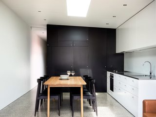 Renovated 19th-Century Terrace House Merges with the Outdoors - Photo 4 of 7 - The home’s minimalist kitchen demonstrates that you can create something beautiful without shelling out too much cash. To help stretch the budget, Abicic installed generic fixtures and cabinets. The dining room chairs and table were purchased secondhand.