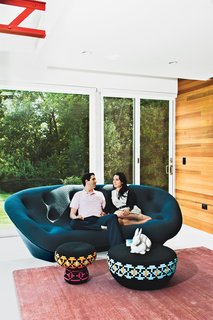 The Midcentury Spirit is Alive and Well in This Hudson Valley Escape - Photo 11 of 11 - Steven and Tata relax in their living room. "The house has always been deemed the ‘great escape,’" says Steven. "It’s a very special place for us." The Superheroes stool and table are by Swedish designers Glimpt Studio for Cappellini, the blush-colored rug is from ABC Carpet & Home, and the Pan Pan rabbit figurine is by Ligne Roset.