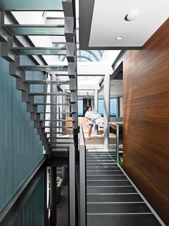 The central stairway spans the entire house from the first floor to the roof, which is crowned by a glass ceiling that allows in extra light. Areas such as the master bedroom, which is open to the living room below, fan off of the staircase, a unifying component.