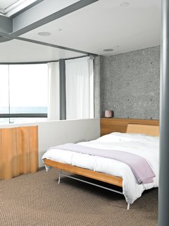 The original bedroom, which Dukes refers to as "very Scarface," included red shag carpet. Dukes toned down the space with a Thin Edge bed by George Nelson and an Eames folding screen.