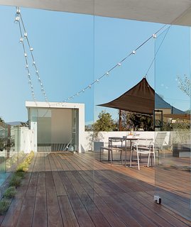 A Minimalist Duplex in Venice, California - Photo 7 of 9 - With a fire pit, mobile shades, and drought-tolerant grasses recessed in the Mangaris plank expanse, the roof deck is a communal space in the duplex. The Kookaburra Shade Sail, made of a woven polymer material that prevents mold, can be moved around as needed.