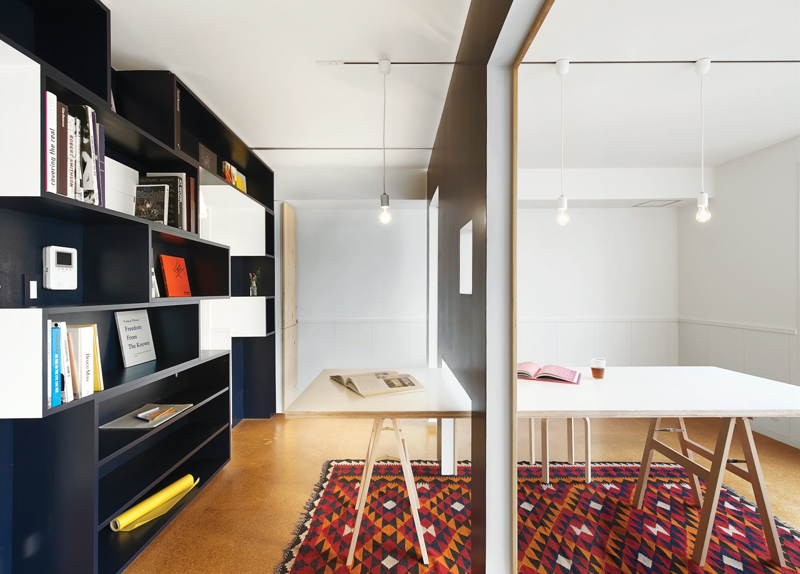 How to Use Modern Home Decor in Unexpected Ways - Photo 9 of 9 - Yuko Shibata made the 10-person dining table using $130 sawhorse legs from Maruki Wood Products Company topped with a sheet of birch plywood. A hole in the sliding wall fits over the table, enabling it to be used in both the library and the meeting room. Then, there's the rug.