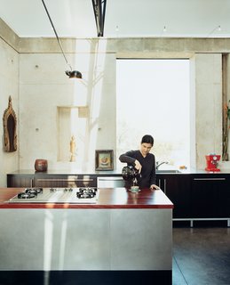 An elegant palette of materials defines the open kitchen. The rear counter is sanded stainless steel; the island counter is Purpleheart (an exotic hardwood) with a range by Dacor.