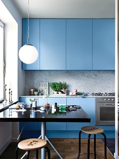 The sink and faucet—notice their reflection in the glass—are by Mora Armatur. Resident Saša Antić purchased the stool from local vintage shop Dusty Deco. A retro Ikea pendant lamp hangs above the kitchen table, which is an architect’s drafting board Antić found at Grandpa, another store in his neighborhood. Photo by: Jonas Ingerstedt