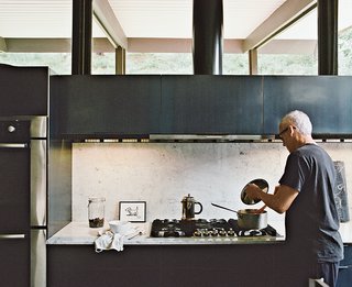 10 Stunning Ways to Use Black in Your Kitchen - Photo 7 of 10 - The couple made the most dramatic changes in the kitchen. They installed Carrara marble and custom oiled-steel cabinetry. The artwork is by Cecil Touchon. Near the Wind Crest cooktop is a Bosch oven.