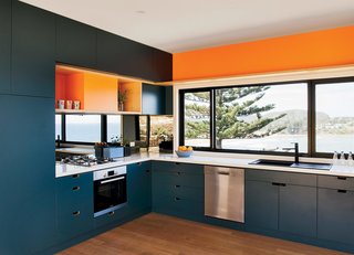Inspired by the sea and sand, the couple chose blue and orange joinery colors. The oven, cooktop, range hood, and dishwasher are by Bosch.