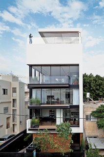 Modern High-Rise Town House in Tel Aviv - Photo 1 of 7 - Tall and surprisingly open, the Tel Aviv Town House by Pitsou Kedem Architects continues in the tradition of its Bauhaus-inspired neighbors with a white facade and black window frames.