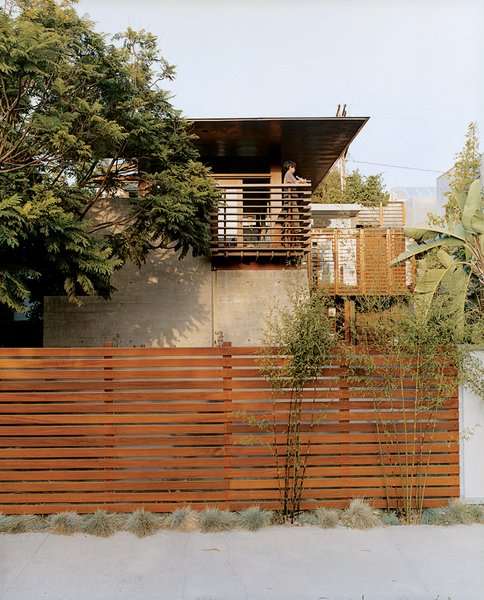 Sustainability in Stages - Photo 2 of 6 - Trellis-like balcony railing cue the exposed timber frame extending over the house. The balcony and fence are made from sustainably harvested ipe wood.