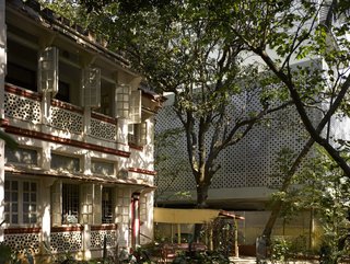 Somewhat by chance, the apartment building's aluminum core references the perforations of the house next door; its interior breezeways also echo those of the neighboring structure.