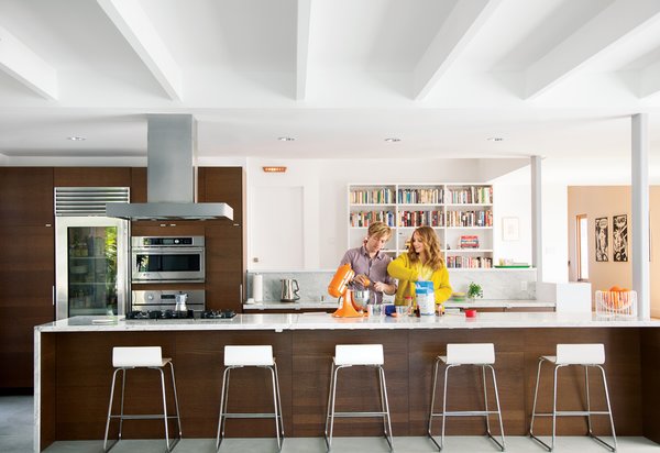 To impart a high-design feel to the kitchen in a renovated Los Feliz house, architect Mike Jacobs wrapped cabinetry from Ikea with a marble countertop and designed built-in bookshelves around the space to help unify the area. The hood is by Zephyr, the cooktop is by Miele, the refrigerator is by Sub-Zero, the ovens are by GE Monogram, and the stand mixer is by KitchenAid. The Sebastian barstools and Trådig fruit bowl are also from Ikea.