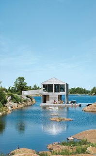 Cedar slats mark the facade of Floating House, Doug and Becca Worple's lake house in Ontario. The architects, MOS, chose materials and shapes that wouldn’t stand out. "They’re really simple, almost Platonic forms," principal Michael Meredith says. The modest cabin has boat, a gabled roof and a cladding of untreated cedar, a material that shows up on docks and homes along Georgian Bay. "Allowing the buildings to weather seems the right thing to do," Sample says. And it’s ready for winter: Sliding barn doors seal the place up as an impenetrable box.