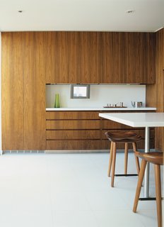 A 13-foot-long island in the kitchen, finished in the same white terrazzo as the floor, serves as an informal dining area. Bassam replicated the kitchen’s walnut-veneered cabinetry in the study and master bedroom for continuity.