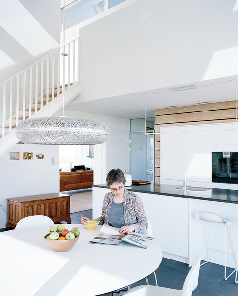 In one Danish family's green-home prototype, the kitchen receives tons of natural light thanks to triple-glazed, argon-filled windows and their super-insulated frames. Sophie sits at the Nava dining table in the kitchen, which is flanked by Gubi chairs and illuminated by the Aeros light by Ross Lovegrove for Louis Poulsen.