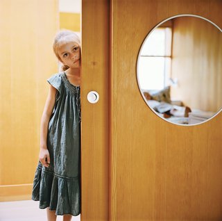 Eight-year-old Emily peeks out from a sliding panel door with matte marine hardware that will age gracefully in the salty air.