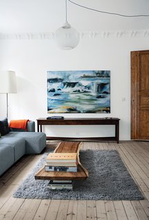 Budget-Friendly Renovation of a Neoclassical Home in Oslo - Photo 1 of 11 - Norwegian architect Casper Mork-Ulnes and his wife, American furniture designer Lexie Damner Mork-Ulnes, tackled a renovation of their 1,300-square-foot apartment in Oslo. To lighten the space, they treated the floors with Flügger’s Trelut lye, then sanded them, oiled them with PNZ Objektöl, and finished them with two coats of wax. In the living room, a reclaimed Indonesian hardwood slab from Buka Design + Hardwoods is the de facto coffee table and the painting is by Casper’s mother, Randi Mork-Ulnes. The gray Mags sectional sofa is from Hay.